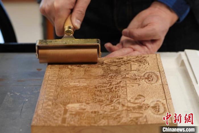 圖為徐晉林工作室工作人員正在給雕好壁畫的版面滾油墨?！【琶赖┰?　攝