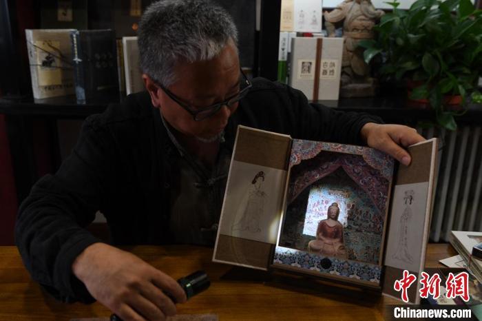 圖為讀者出版集團(tuán)讀者晉林工作室獨(dú)立出品人徐晉林，展示互動(dòng)性強(qiáng)的敦煌題材手工書。(資料圖) 楊艷敏 攝
