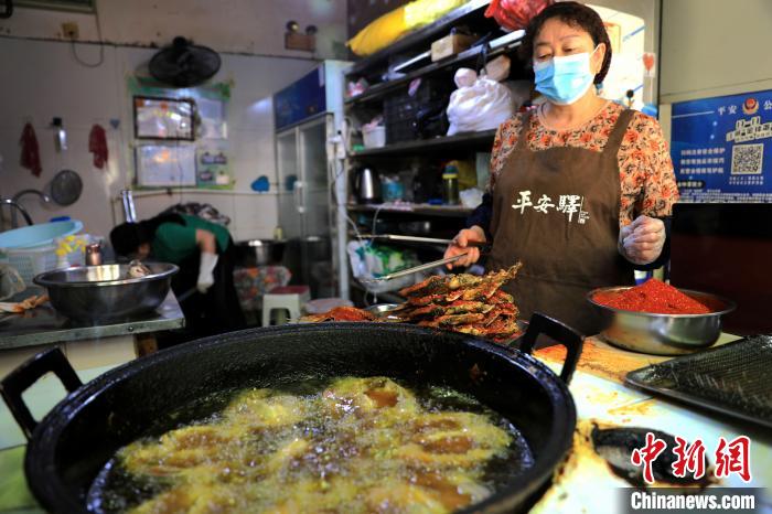 圖為平安驛·河湟民俗文化體驗地內(nèi)的商戶炸干板魚。　薛蒂 攝